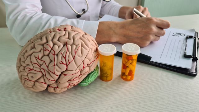 Doctor writing prescription beside brain model and pill bottles representing ADHD medicines. 