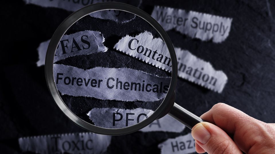 A magnifying glass highlights words like "PFAS," "Forever Chemicals," and "Contamination" on torn paper.