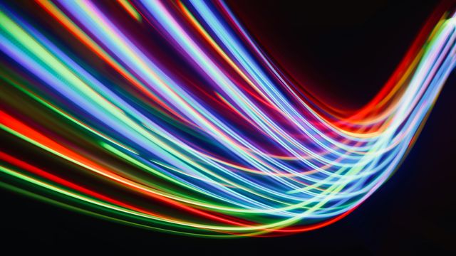 A slightly blurred photo of multi-colored light trails in a dark environment. 