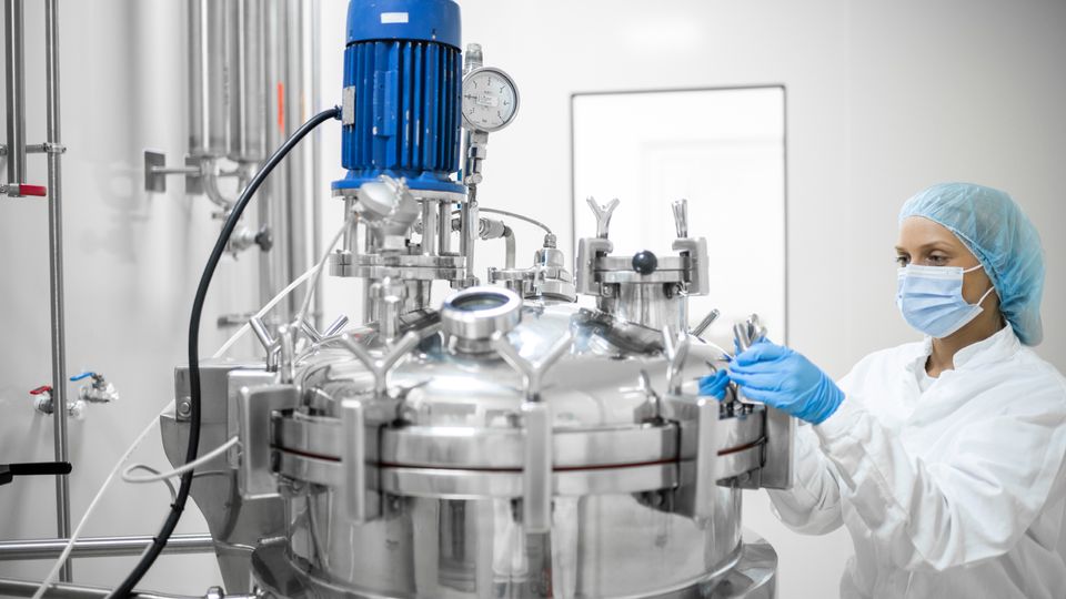A scientist working on a bioreactor before performing downstream processing of the biopharmaceutical product.