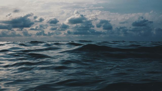 The navy blue waves under a cloudy sky.