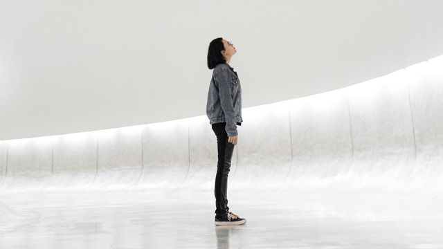 A person standing in a minimalist, modern space, gazing upward, symbolizing curiosity and the future of science. 