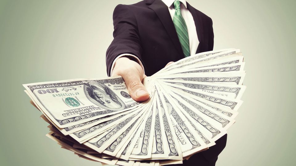 Business man in suit holding money in a fan shape.